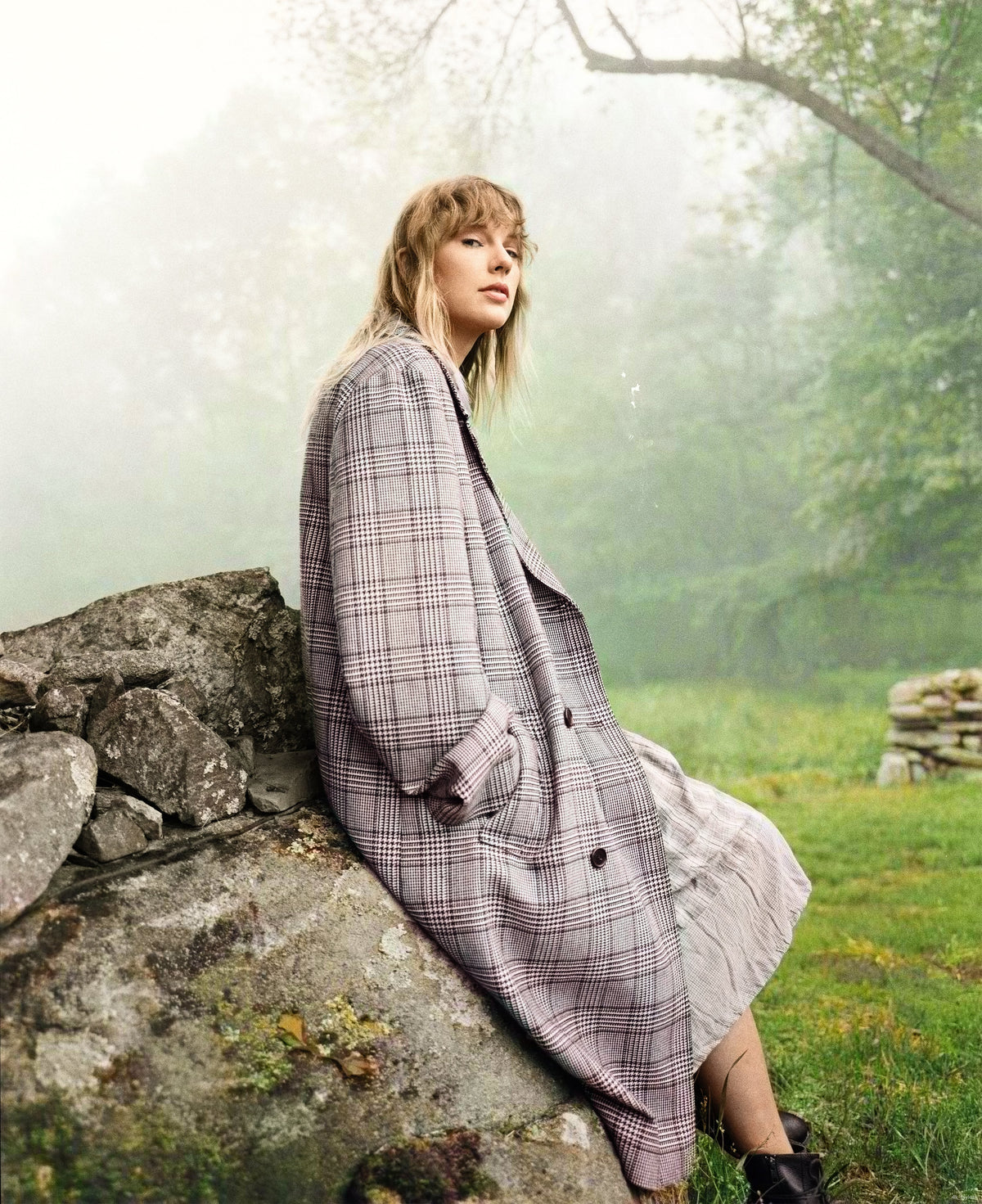 Folklore editorial portrait beside a stone wall in a misty green landscape